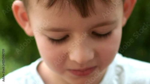 A boy with blond hair eats raspberries on a sunny day outside. healthy food. natural vitamins