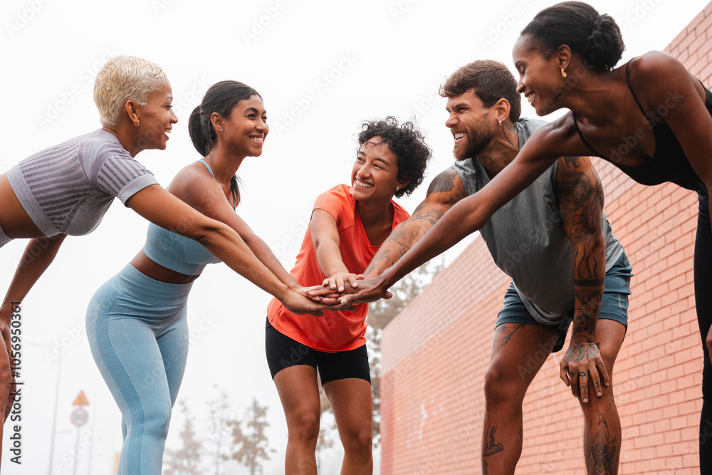 Fototapeta premium Happy athletes joining hands before training in the city