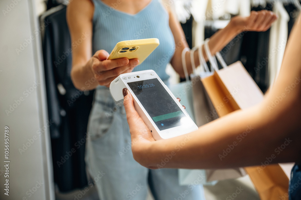 Wireless payment. Woman is paying for clothes, in the retail store Wireless payment. Woman is paying for clothes, in the retail store