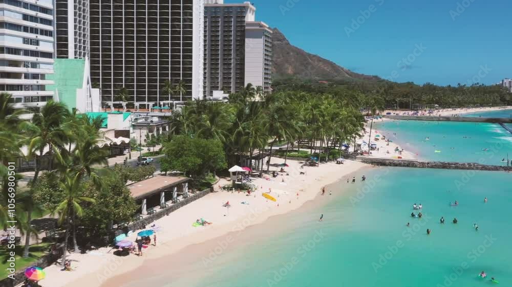 Aerial drone shot of Hawaii city with tall buildings lining the beach, palm trees, and turquoise waters on sunny day, showcasing vibrant coastal scene. Aerial drone shot of Hawaii city with tall buildings lining the beach, palm trees, and turquoise waters on sunny day, showcasing vibrant coastal scene.