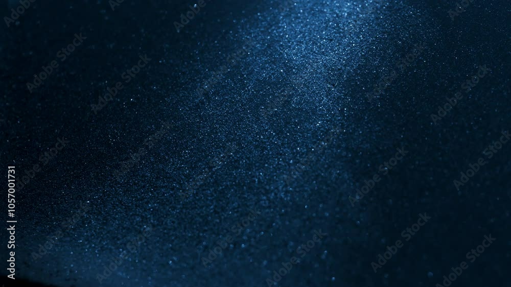 Little grains of sand falling in abstract slow motion under blue light. Little grains of sand falling in abstract slow motion under blue light.