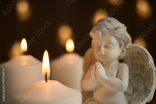 A statue of an angel with burning candles in close-up. A memory of loss. Prayer. photo