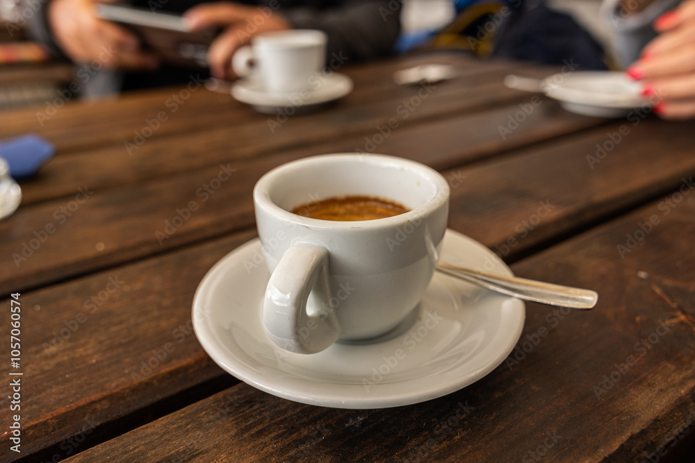 tazzina bianca piena di caffè espresso, al bar, su un tavolo di legno, di giorno