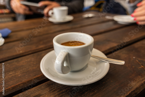 Obraz na płótnie tazzina bianca piena di caffè espresso, al bar, su un tavolo di legno, di giorno w salonie