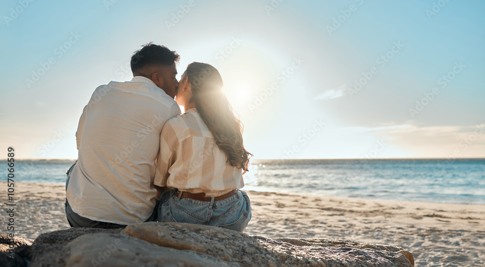 Fototapeta premium Kiss, beach and back of couple relax on getaway, vacation or holiday for romance together. Love, travel and man and woman sitting on sand by tropical ocean on seaside date on summer weekend trip.