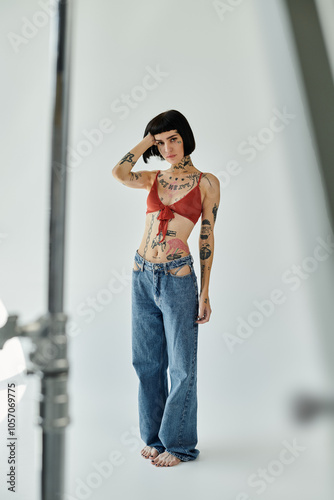 Fashionable woman showcases her tattoos while striking a pose in casual wear.