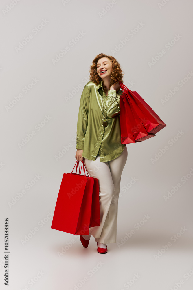 A happy young woman wearing a green shirt is packing gifts and holds red shopping bags. A happy young woman wearing a green shirt is packing gifts and holds red shopping bags.