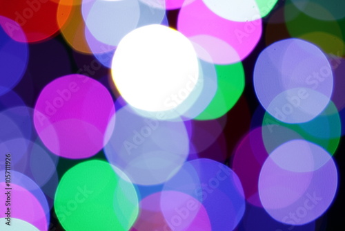 Una toma de cerca de una fondo abstracto de luces de navidad de diferentes colores en la oscuridad. Desenfoque bokeh