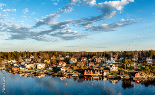 Small idyllic port in the Swedish archipelago outside of Stockholm with beautiful reflection lighted with sunspot at autumn evening. photo