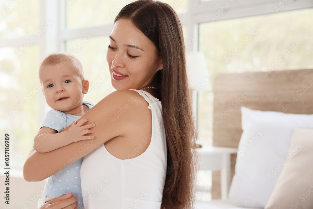 Beautiful young happy Asian mother with her cute little baby in bedroom at home Beautiful young happy Asian mother with her cute little baby in bedroom at home