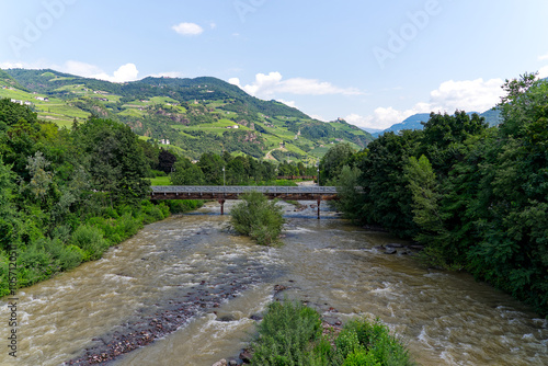 Scenic view of Talfer Tavera river with bridge and mountain panorama in the background at Italian City of Bozen on a sunny summer day. Photo taken July 17th, 2024, Bolzano Bozen, Italy. photo