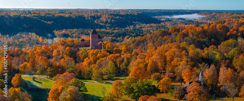 Aerial view of Sigulda, Latvia, featuring Turaida Castle amidst vibrant autumn foliage. The Gauja River Valley adds depth with its misty background. photo