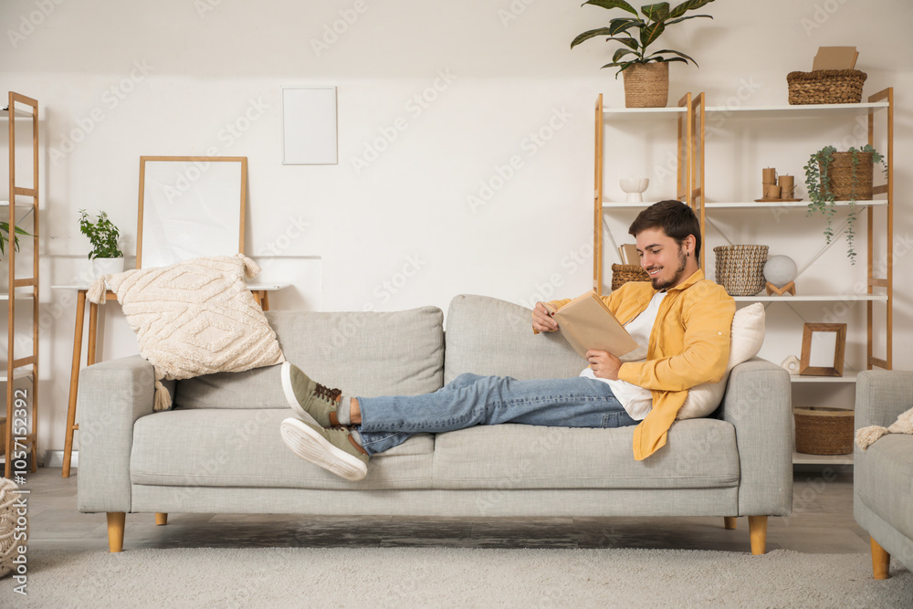 Young man reading book on sofa at home Young man reading book on sofa at home