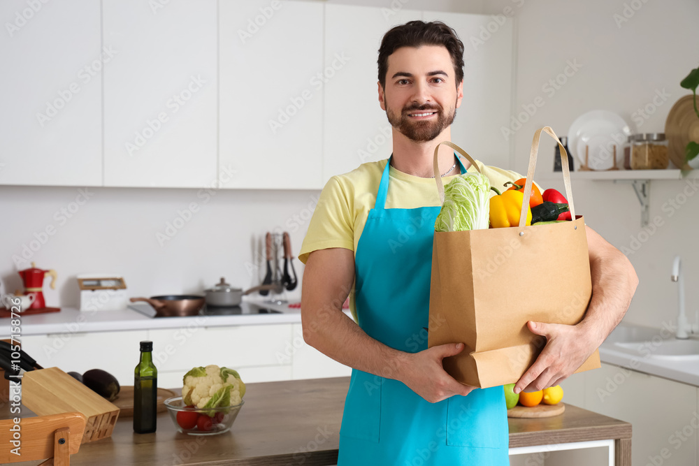 Handsome bearded man with bag of food in kitchen Handsome bearded man with bag of food in kitchen