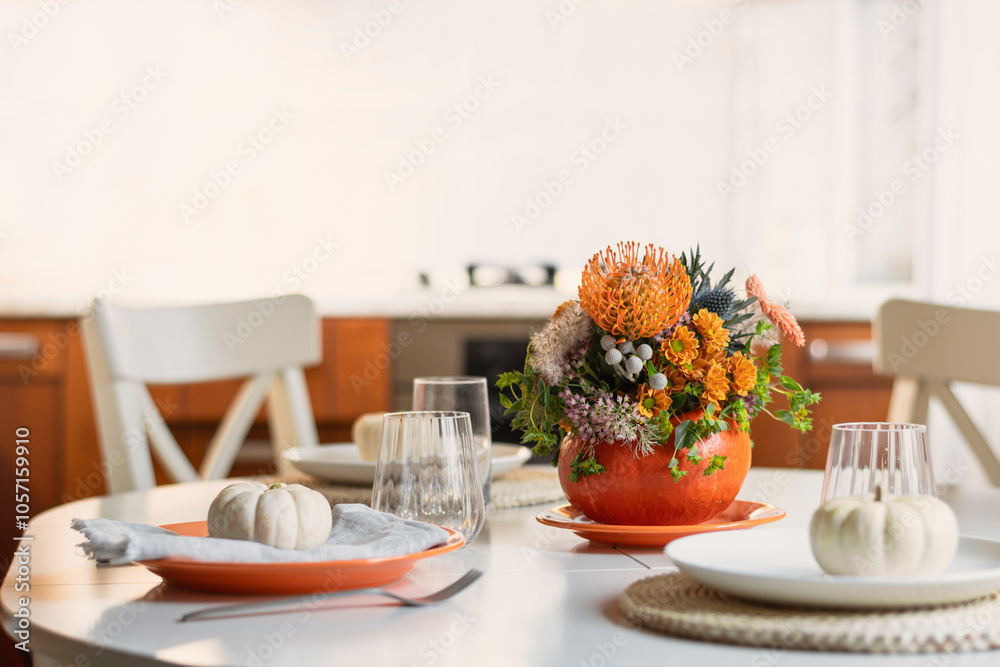Thanksgiving day table setting decoration beautiful centerpieces with orange flowers in pumpkins on white table in home kitchen interior. Close up. Thanksgiving day table setting decoration beautiful centerpieces with orange flowers in pumpkins on white table in home kitchen interior. Close up.