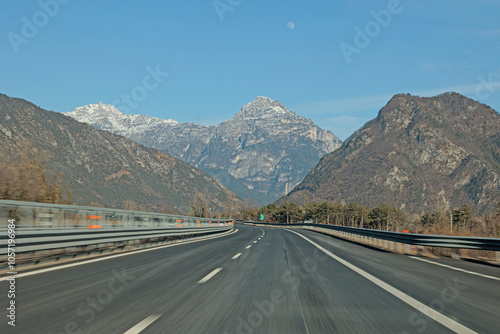 viaggiare in autostrada, in mezzo alle montagne del nord Italia, di giorno, in inverno, con cielo sereno photo