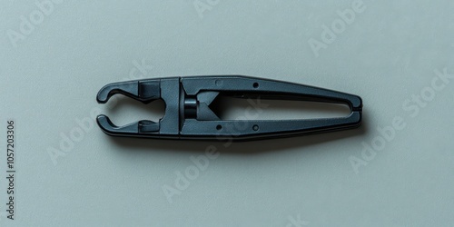 One black staple remover isolated on a solid gray background, top view. photo