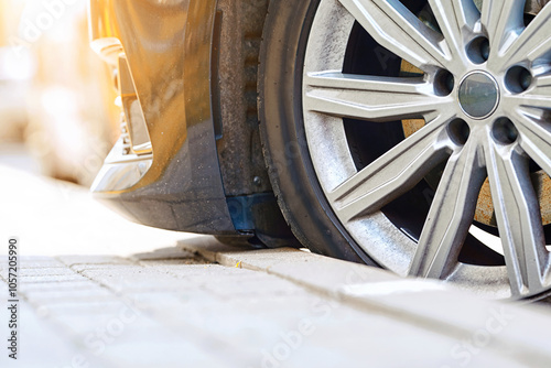Car parked close to the curb. Risk of scratching the bumper while parking and damage tire. Low clearance, tire and bumper closeup.