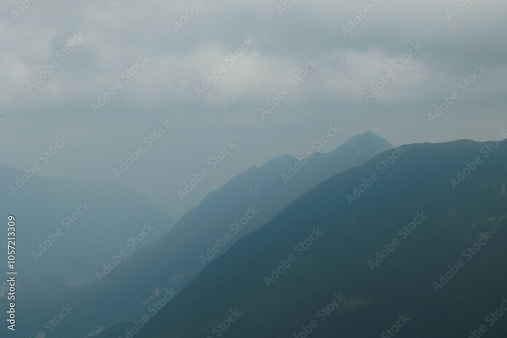 Obraz premium dettaglio di varie catene montuose nelle Alpi italiane che si estendono in lontananza verso l'orizzonte, avvolte da una fitta foschia e con un cielo nuvoloso