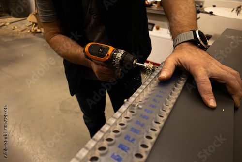 The carpenter drills the holes with an electric screwdriver