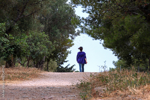 back view of a woman walking in a park in Athens, Greece. sunny day