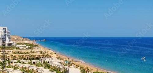 panoramic aerial view of Fujairah coastline with beach hotels lining the shore and the clear sea, UAE