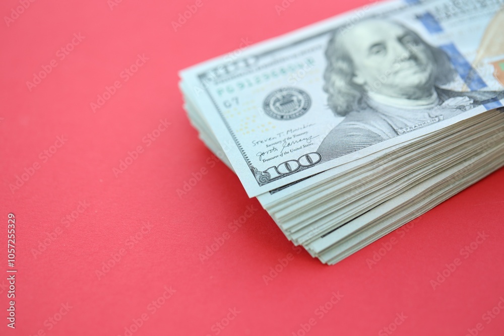 Big amount of hundred dollar bills in thick stack lies on bright red color paper background Big amount of hundred dollar bills in thick stack lies on bright red color paper background