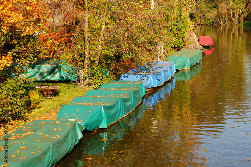 Die Spreewaldkähne liegen abgedeckt am Ufer der Fließe im Herbst photo