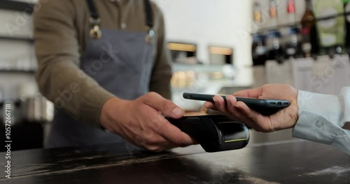Close up in the cafe man makes takeaway coffee for a customer who pays by contactless mobile phone to credit card system in cafe with digital transaction service.