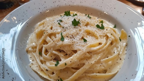 Fettuccine Alfredo served in a creamy sauce with fresh parsley and grated parmesan on a white ceramic plate