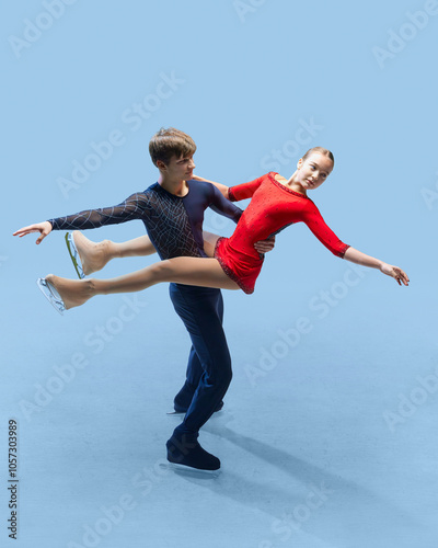 Dynamic photo of two figure skaters perform an elegant lift against cold blue background, illustrating strength and grace of competitive skating. Concept of sport, elegance and grace, championship. Ad photo