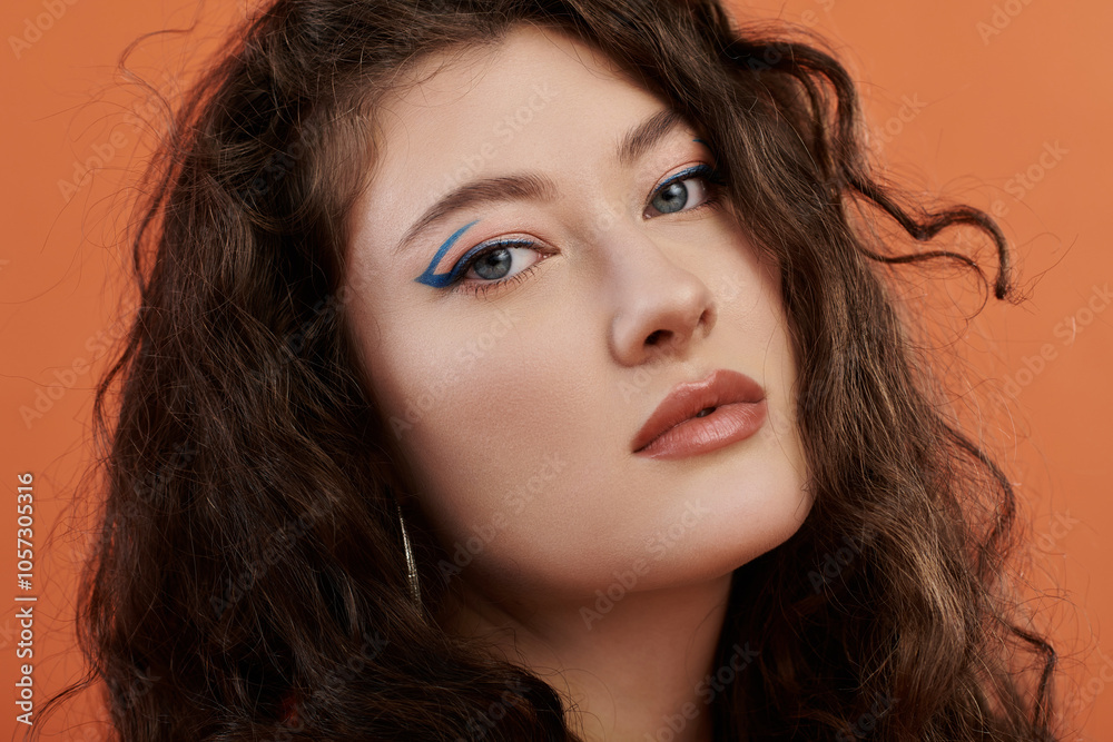 A beautiful plus size woman showcases her style and confidence against a bold orange backdrop. A beautiful plus size woman showcases her style and confidence against a bold orange backdrop.