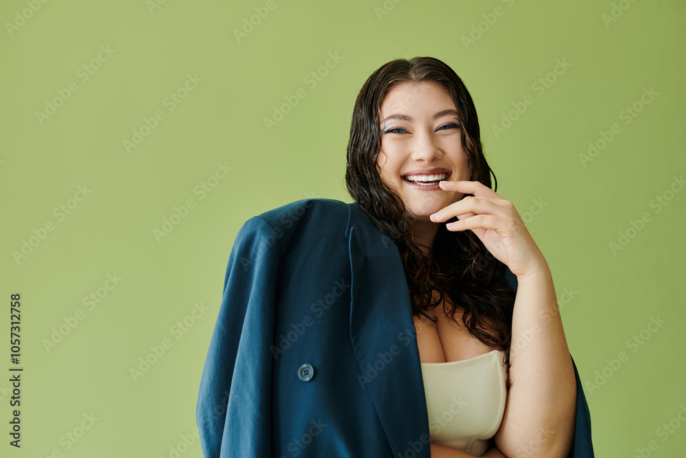 A young, beautiful plus size woman with curly hair showcases her confidence in a suit against a bright green backdrop. A young, beautiful plus size woman with curly hair showcases her confidence in a suit against a bright green backdrop.