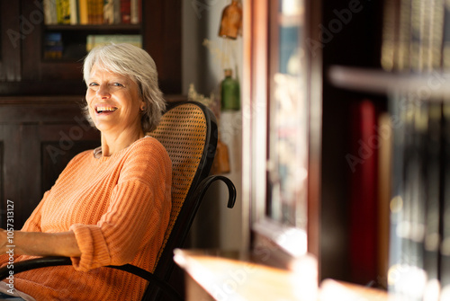 Happy woman in orange sweater relaxing in a cozy home library