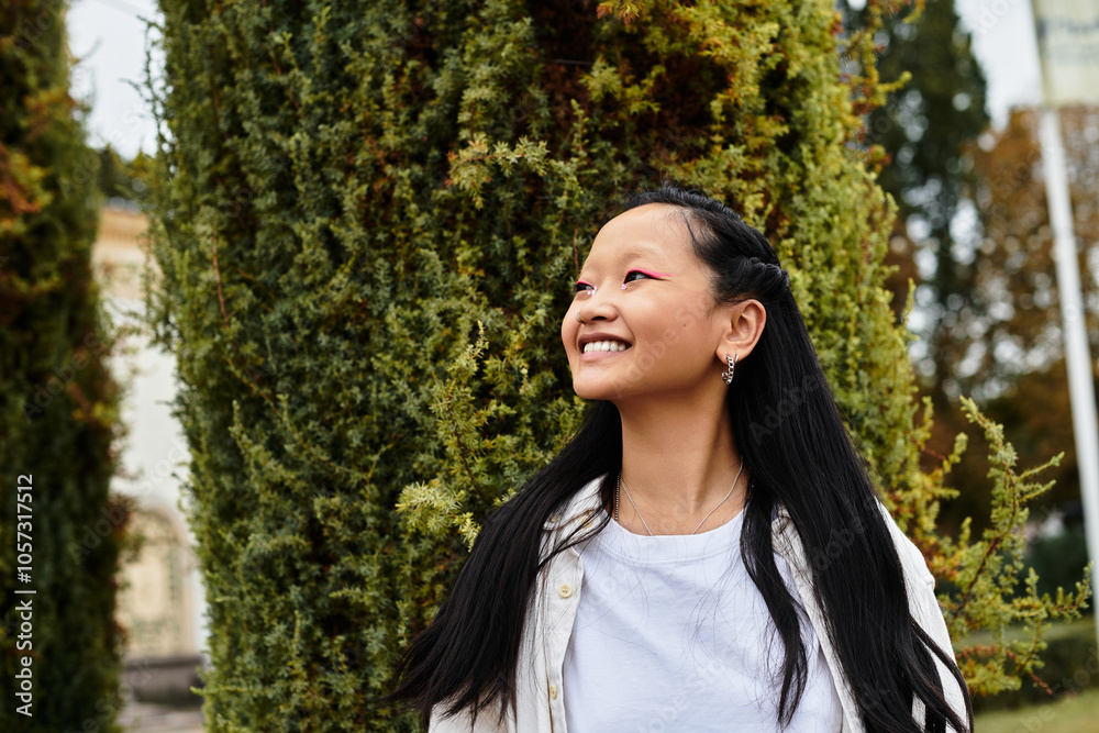 A cheerful young Asian student stands near the university campus, showcasing her fashionable outfit and joy. A cheerful young Asian student stands near the university campus, showcasing her fashionable outfit and joy.
