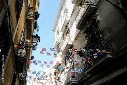 Colorful International Flags Hanging Across Narrow European Street Between Historic Buildings