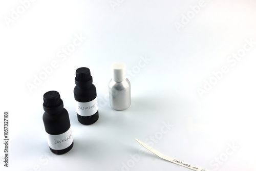 amber color essential oil bottle is on white table with blotting paper , fragrance bottle and digital scale are used to blend the nice scent for making perfume and candle by perfumer in laboratory	