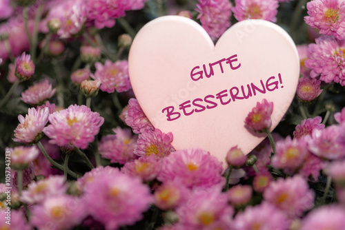 Herz in weiß zmit text Gute Besserung in deutsch zwischen Blumen in pink photo