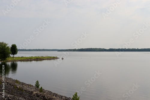 The calm lake in the country on a foggy sunny day.