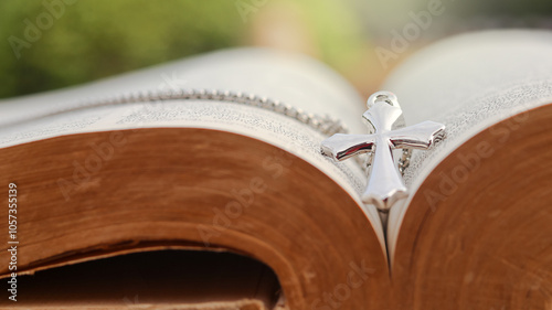 Shiny metal cross leaning against an old open book symbolizing the spread of Jesus Christs love among Christians reflecting faith devotion and the importance of Christian teachings.