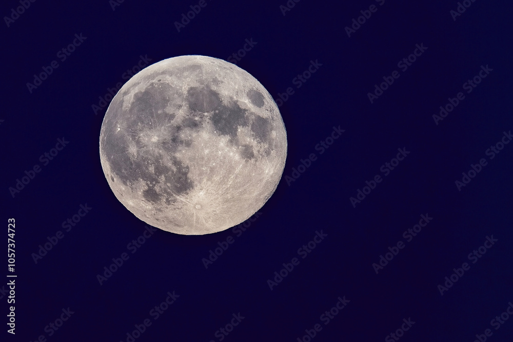Full moon shining in the dark blue night sky.