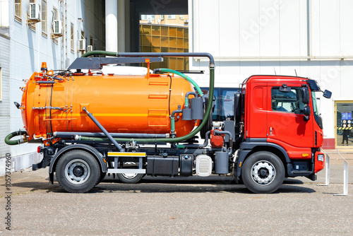 Obraz na płótnie Modern orange and red sewage truck parked near industrial building. w salonie
