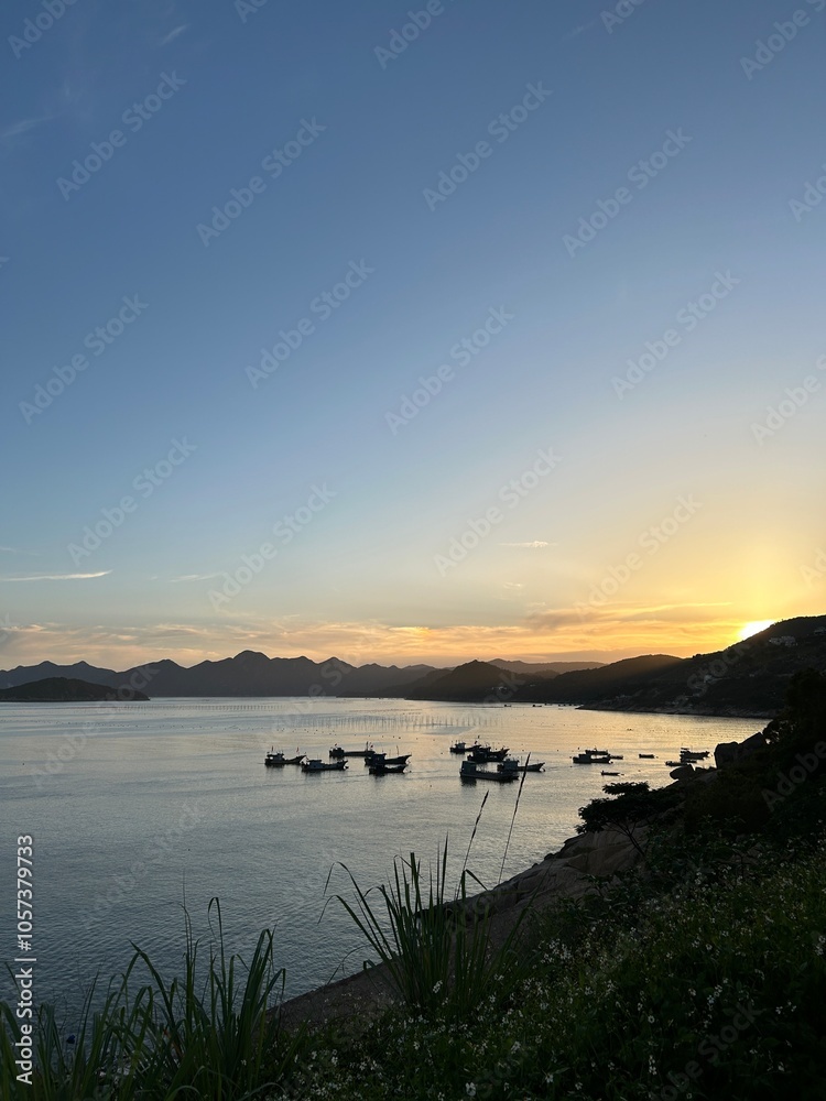 Fototapeta premium Warm Sunset over Quiet Bay with Docked Boats and Dark Hills.