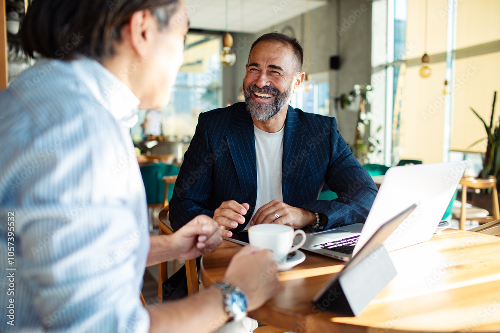 Businessmen discussing strategy over coffee in modern cafe setting
