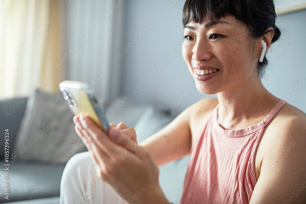 Asian woman relaxing on couch using smartphone app at home Asian woman relaxing on couch using smartphone app at home