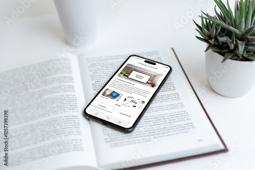 Phone displaying online courses app on a book, symbolizing creative writing education. Ideal for visuals on digital learning, writing skills, online courses, and education tools. photo