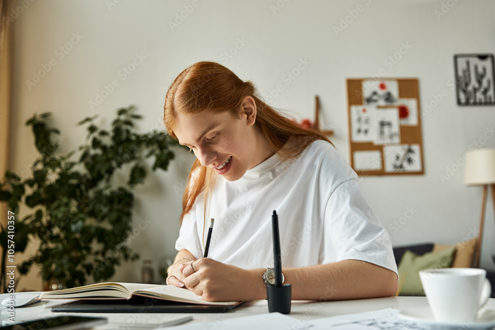 A cheerful young man writes enthusiastically in his notebook at a stylish workspace. A cheerful young man writes enthusiastically in his notebook at a stylish workspace.