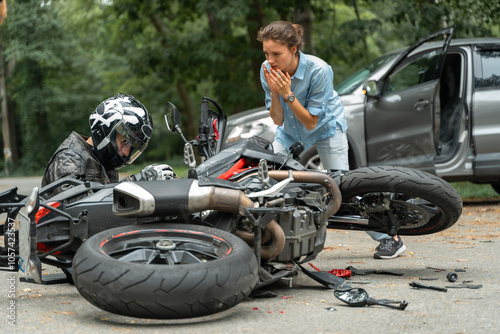 Collision between motorcycle and car on the road. Girl driver hit motorcyclist. Broken and wrecked motorcycle on road photo