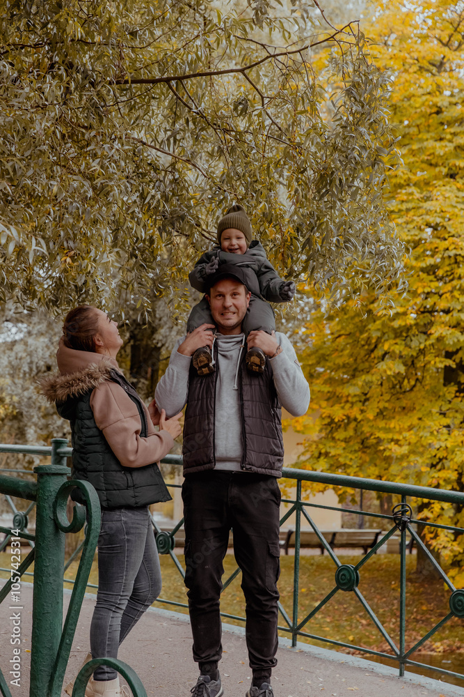 Family in nature in an autumn park with a child on bridge