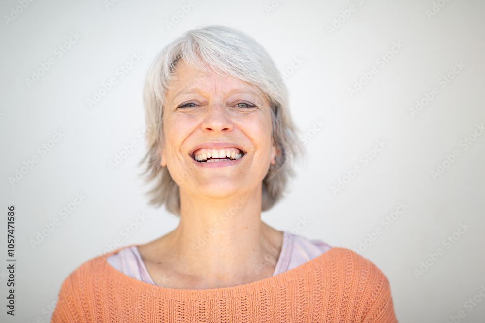 Smiling woman in orange sweater with short gray hair on white background Smiling woman in orange sweater with short gray hair on white background
